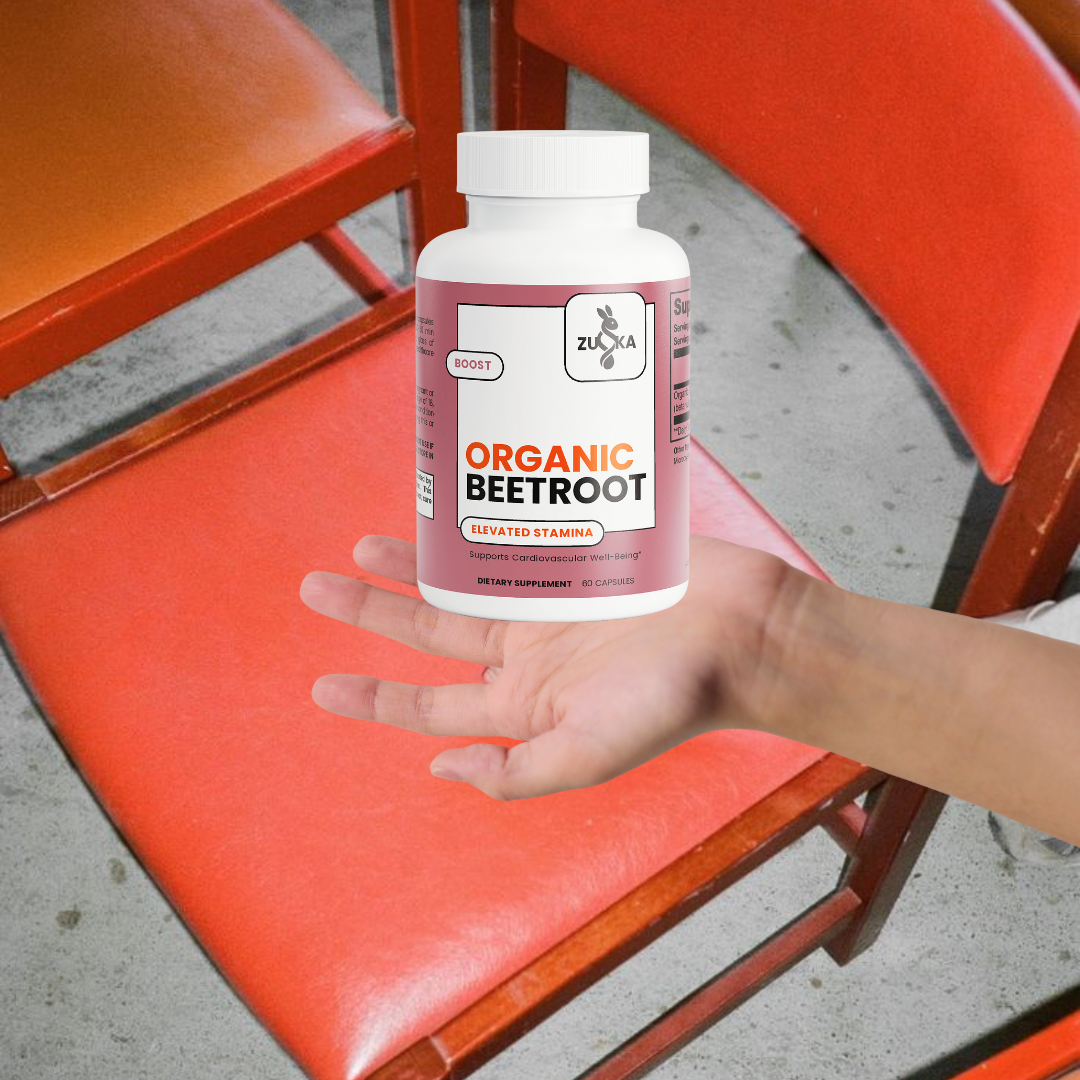 Hand holding a bottle of Zuika Organic Beetroot supplement on a red chair.